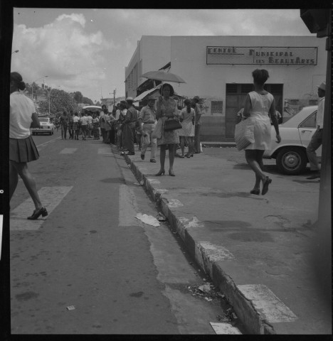 Fort-de-France, centre-ville. scènes de vie quotidienne : passagers attendant le bus ; rue et ses caniveaux