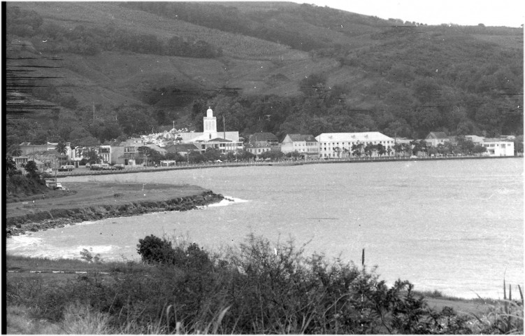 Trinité. scène de vie quotidienne : logement au milieu rural (case traditionnelle en bois), enfants et parents ; vue sur le littoral : baie