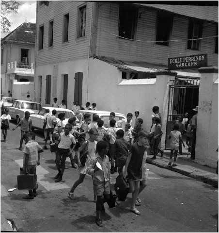 Trois sujets de reportage : sortie d'enfants de l'école Perrinon, un marché du centre-ville, sortie d'un temple évangéliste devant l'arrêt des taxis collectifs de la compagnie T.U.M.A