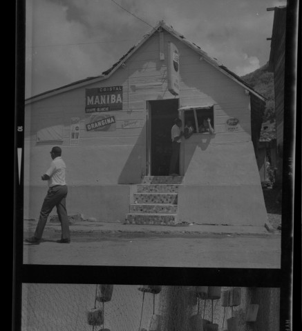 Le Carbet. Bar-café avec des enseignes publicitaires ; pêcheurs arrangeant leurs filets et leurs canots